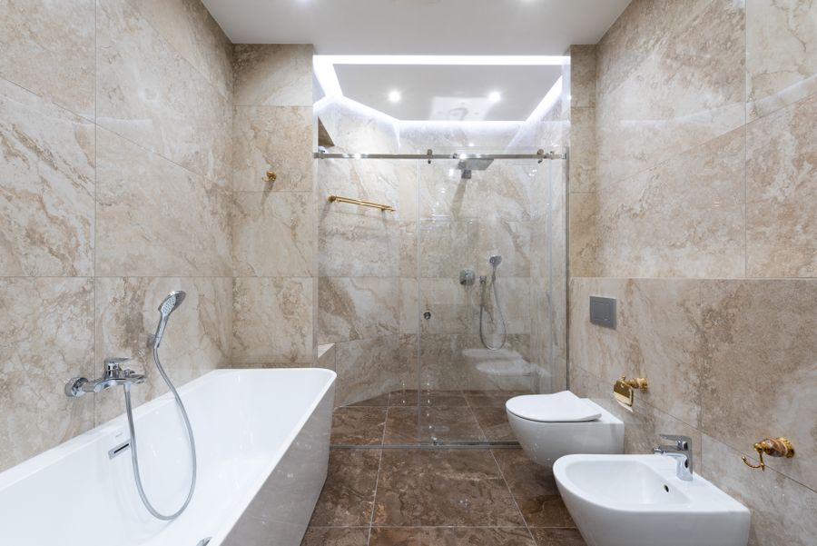 Marble bathroom with a toilet and bidet used to illustrate an imaginary executive suite